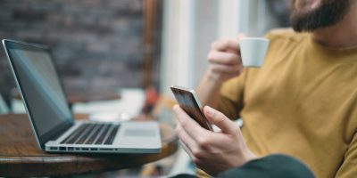 Young man sitting in cafe and using smart phone.